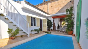 Una piscina con una escalera blanca y plantas en macetas.