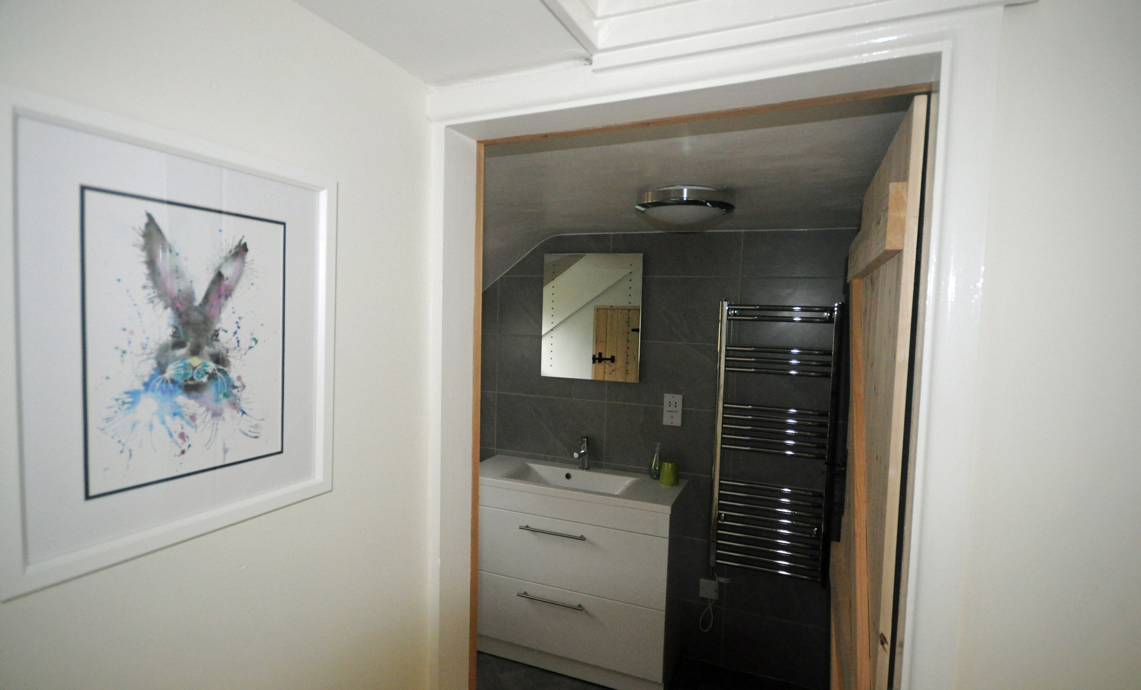 A bathroom with a white sink, a mirror, and a towel rack.