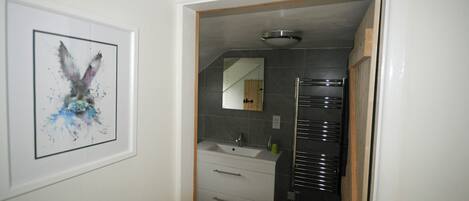 A bathroom with a white sink, a mirror, and a towel rack.