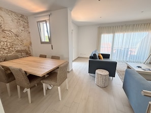 Una sala moderna con comedor, un sofá, una mesa de centro y un otomano estampado.