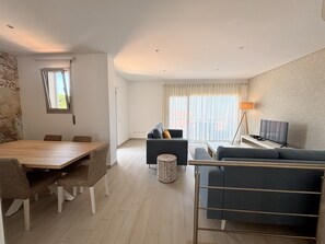 Ein modernes Wohnzimmer mit Essbereich, einer Couch, einem Fernseher und einer Lampe.