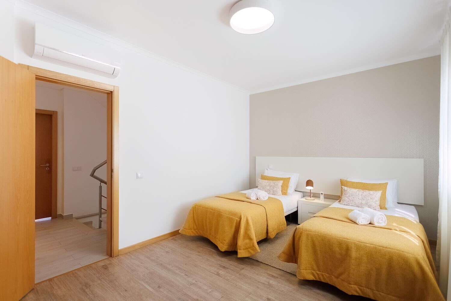 A hotel room with two beds, a wooden door, and a white ceiling.