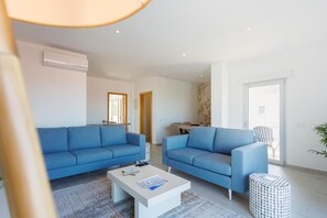 Una sala de estar moderna con dos sofás, una mesa de centro y un comedor al fondo.