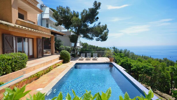 A swimming pool with a view of the sea, surrounded by greenery and a building with a terrace. - Holiday rental villa with swimming pool in Tamariu, Tamariu (Tamariu)