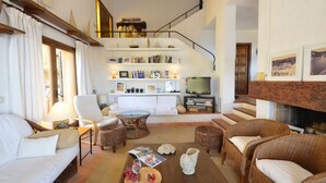 A spacious living room with a sofa, chairs, a coffee table, and a fireplace. There is a staircase leading to an upper level. - Holiday rental villa with swimming pool in Tamariu, Tamariu (Tamariu)