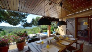 A wooden table set for breakfast with a view of the mountains. - Holiday rental villa with swimming pool in Tamariu, Tamariu (Tamariu)