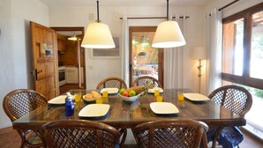 A dining area with a glass table, wooden chairs, and a fruit bowl. - Holiday rental villa with swimming pool in Tamariu, Tamariu (Tamariu)
