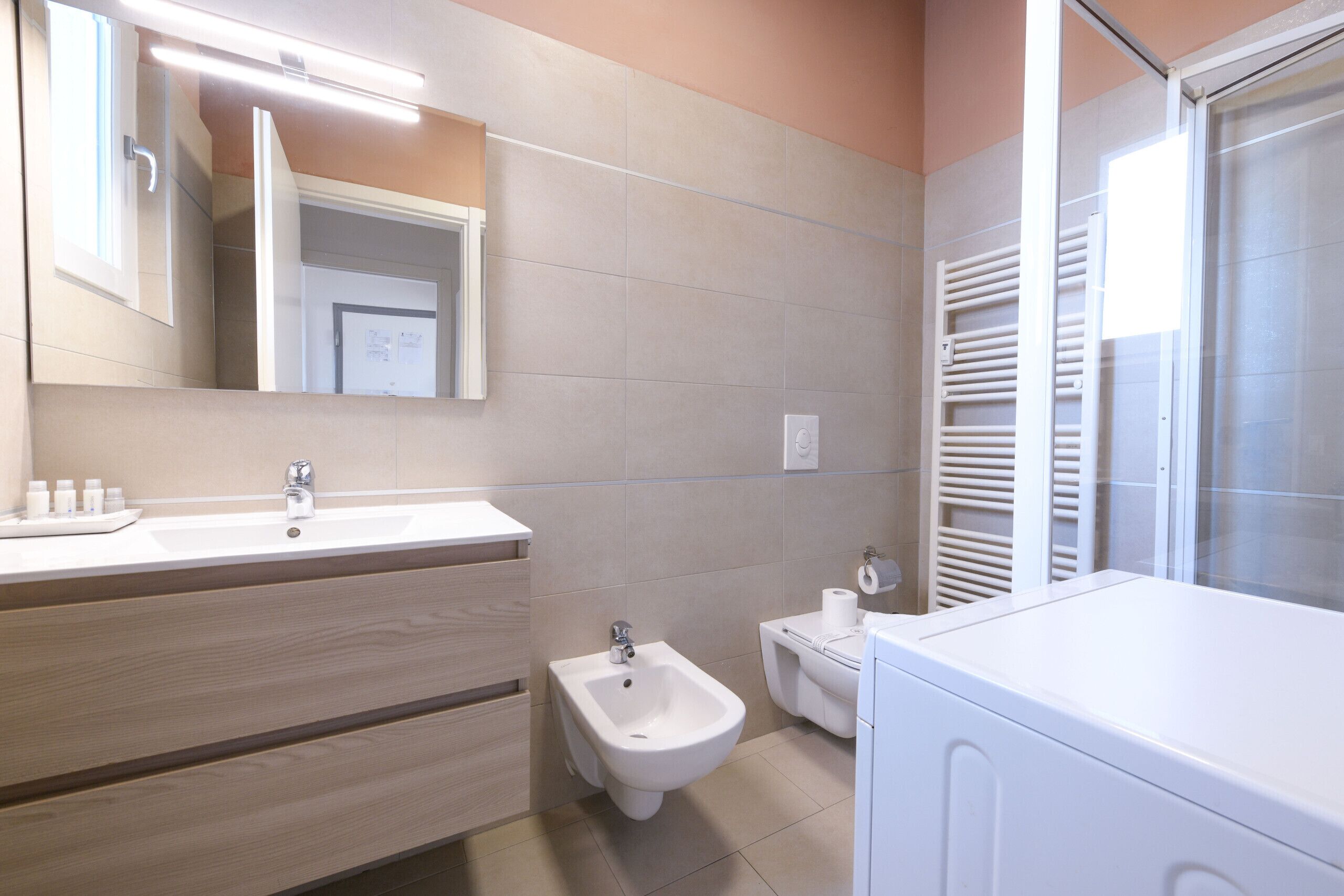 Un bany modern amb rentatge, bidet, vàter i mirall.