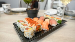 En tallerken sushi med forskellige toppings, en potteplante og et glas champagne på et bord.