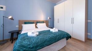 Et soveværelse med seng, sengeborde, en garderobe og et lille bord.