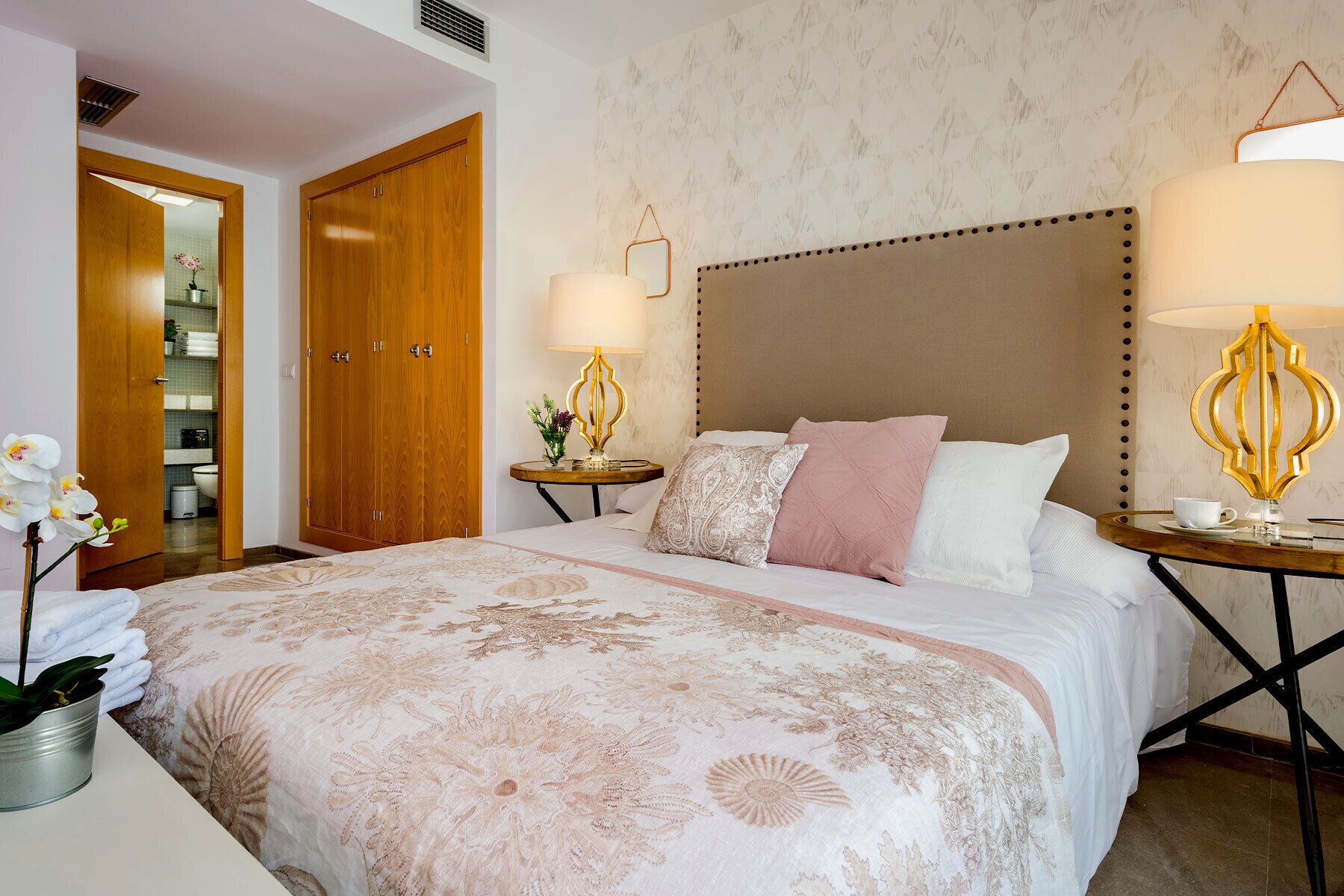 Ein Hotelzimmer mit einem Bett, zwei Nachttischen, einem Holzschrank und einem durchgegangenen Tür zu einem Badezimmer.
