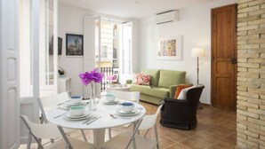 A dining area with a round table set for four, a green sofa, and a black armchair.