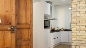 A kitchen with white cabinets, a stainless steel oven, and a brick wall.