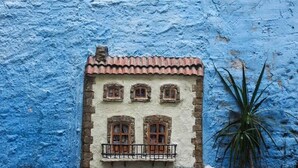 A building with a blue exterior wall and a balcony with a railing.
