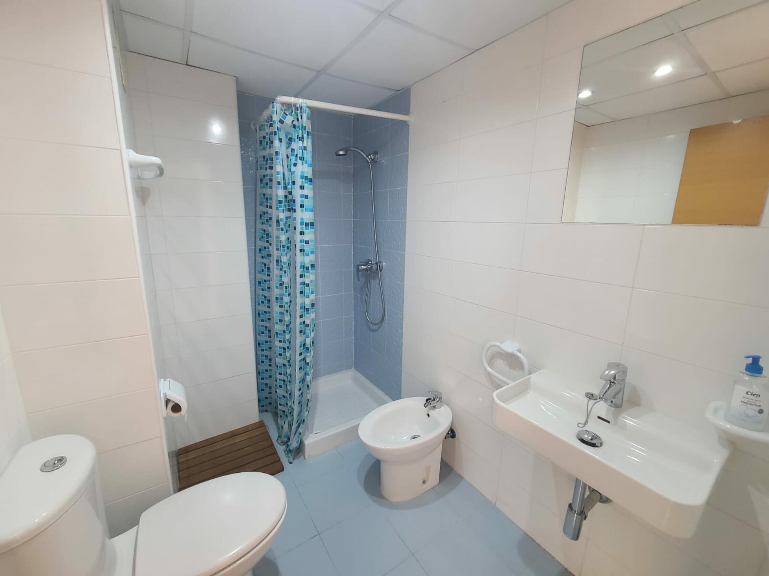 Een badkamer met douche, toilet, bidet en wastafel.
