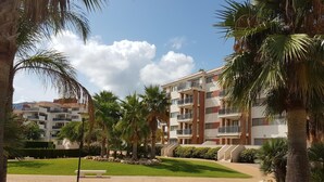Un edificio residencial con varios balcones, rodeado de palmeras y un césped bien cuidado.