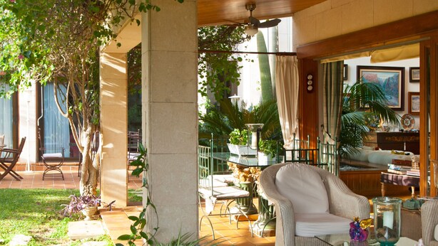 Une vaste terrasse dotée de mobilier d’extérieur, d’une table en verre et d’une variété de plantes en pot.