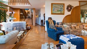 Un salon spacieux avec un escalier, un grand tableau et un coin salon confortable.