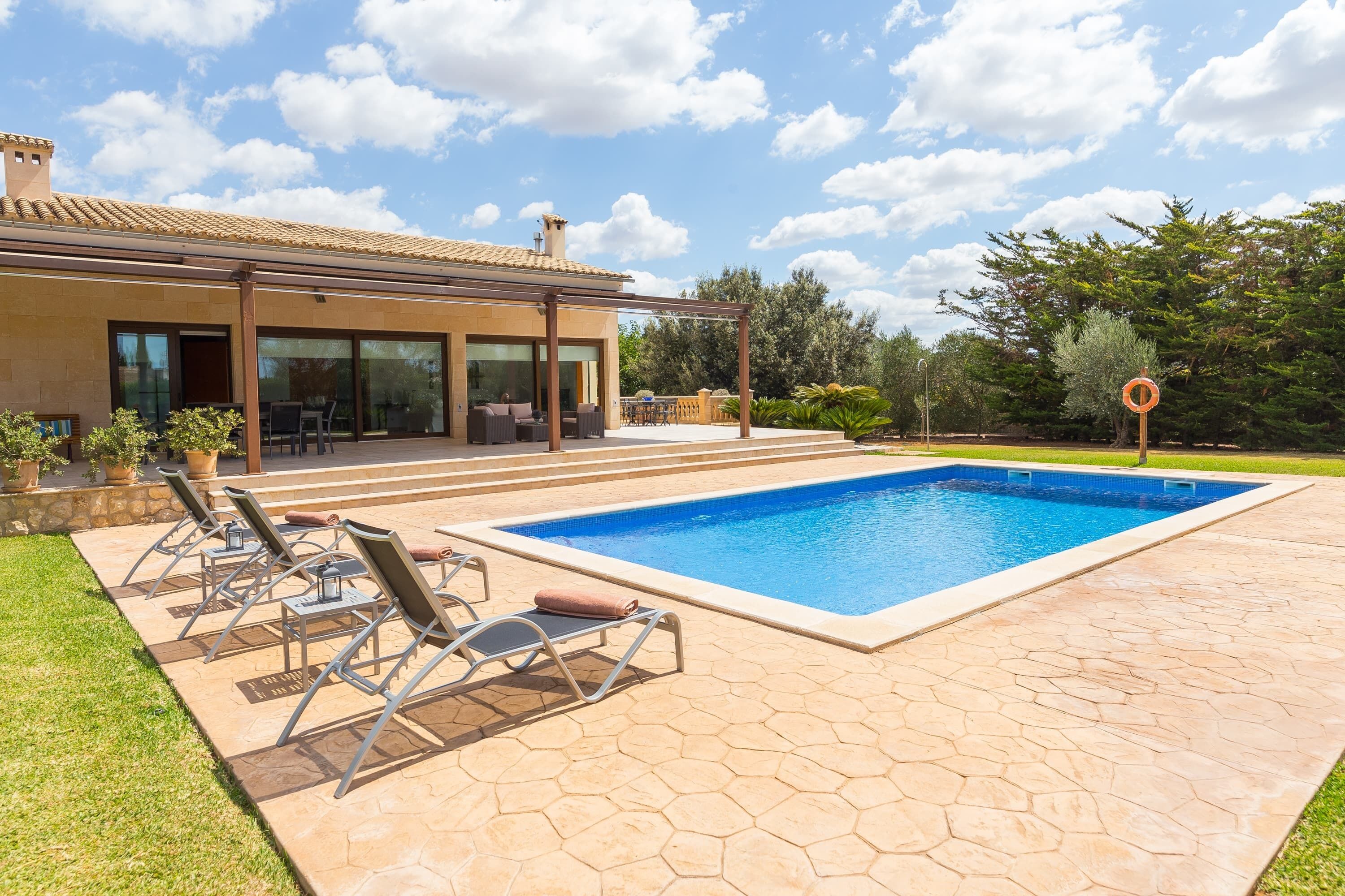 Ein modernes Haus mit Swimmingpool, Sitzgelegenheiten im Freien und einem Garten.