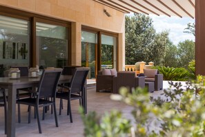 An outdoor patio with a dining table and chairs, wicker furniture, and a view of the surrounding garden and trees. - Es Rasquell - Spectacular villa on the outskirts of Inca (Inca)