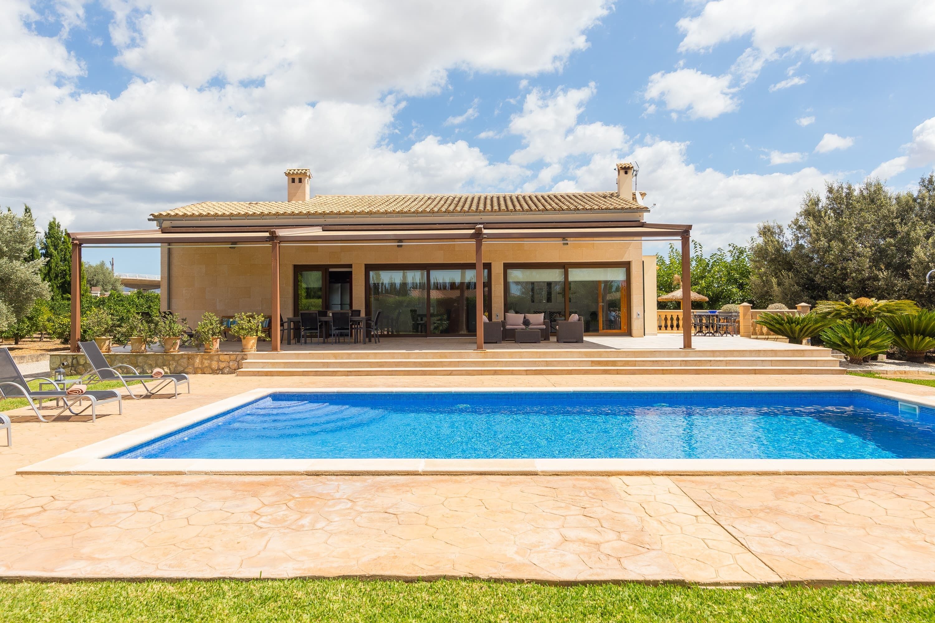 Una casa moderna amb piscina, mobiliari exterior i una zona de pati coberta.