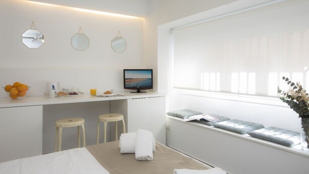 Habitación de hotel moderna con una cama, un escritorio con computadora, dos taburetes, una ventana con vistas y una mesita con toallas.
