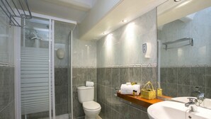 Un baño moderno con ducha de vidrio, inodoro y lavamanos con espejo.