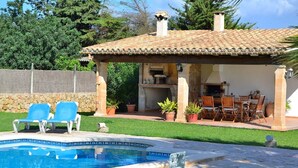 A swimming pool with two lounge chairs, a covered patio with outdoor furniture, and a stone wall. - Can Roig Gran 041 magnificent finca with private pool, large barbecue area and WiFi (Pollensa / Pollença)