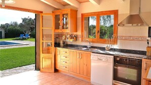 A kitchen with wooden cabinets, a dishwasher, an oven, and a large window. - Can Roig Gran 041 magnificent finca with private pool, large barbecue area and WiFi (Pollensa / Pollença)