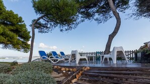 A wooden deck with lounge chairs and a view of the sea. - Las Gaviotas - Spectacular beachfront villa with garden in Platja de Muro (Muro (Platja de Muro))
