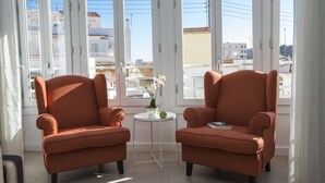 A room with two orange armchairs and a small white table with a vase of flowers.