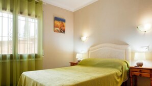 Een keurig opgemaakt slaapkamer met een bed, twee nachtkastjes, een lamp en een schilderij aan de muur.