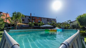 Ein Schwimmbecken mit klarem Wasser, umgeben von Palmen und Gebäuden.