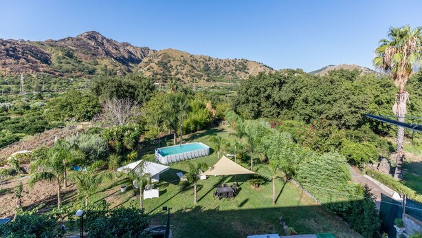 Ein Pool, umgeben von üppiger Vegetation und Hügeln im Hintergrund.