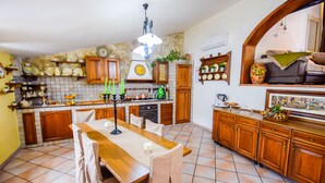 Eine geräumige Küche mit Holzschränken, Fliesenboden und einem Essbereich mit Tisch und Stühlen.