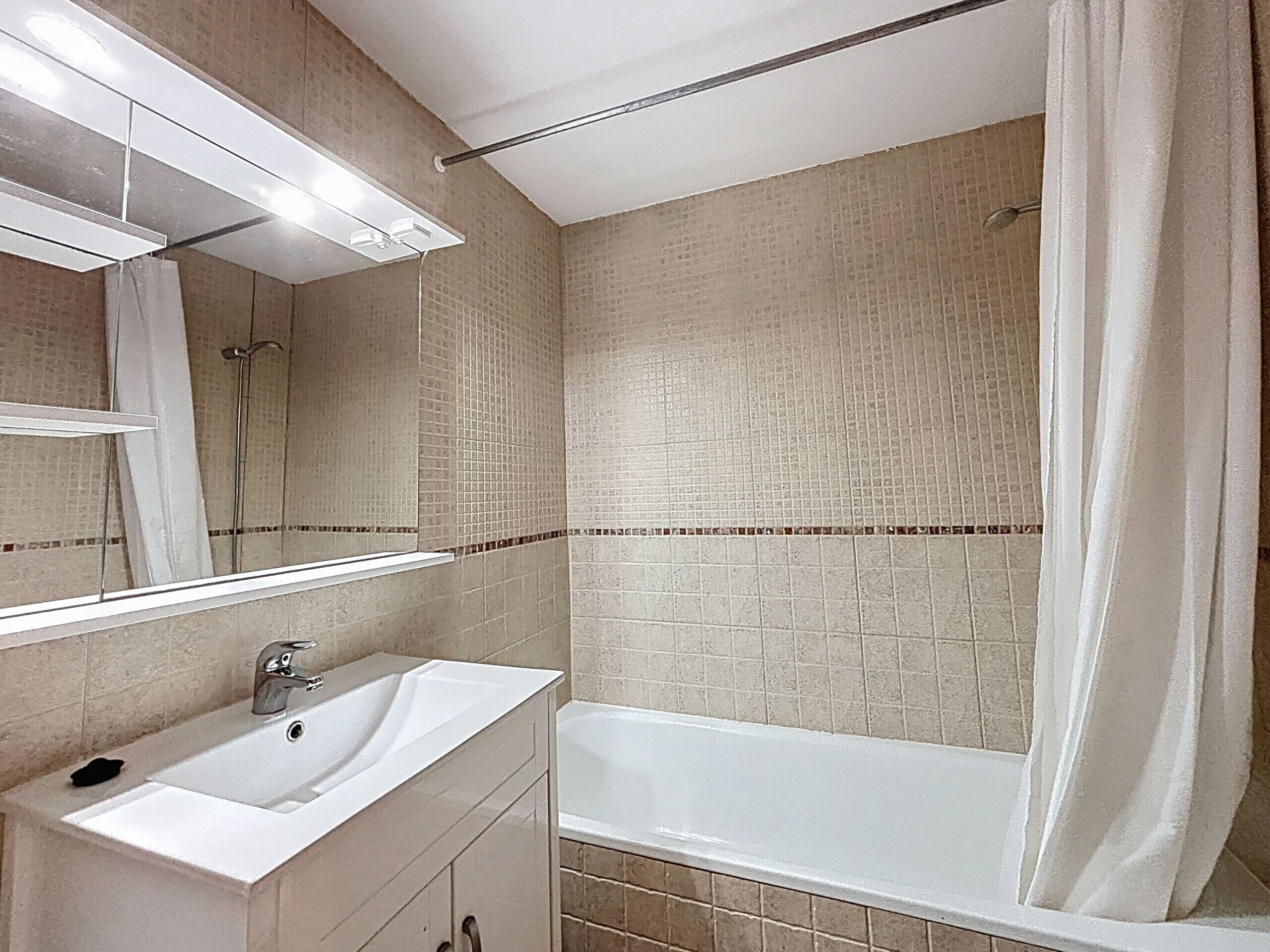 Ein Badezimmer mit einem weißen Waschbecken, einem Spiegel und einer Badewanne.