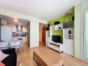 A compact living space with a kitchenette, a dining area, a TV stand, and a sofa.