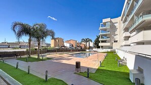 Ein moderner Hotelinnenhof mit Swimmingpool, Palmen und blauem Himmel.
