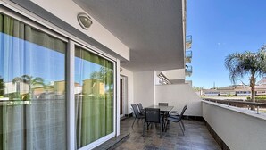 Ein Balkon mit Tisch und Stühlen, eine Schiebeglastür und Blick auf die Stadtlandschaft.