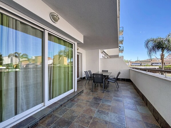 A balcony with a table and chairs, a sliding glass door, and a view of the cityscape.