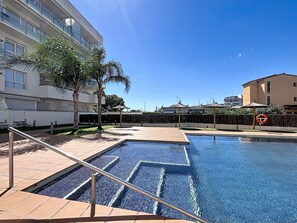 A swimming pool with a metal railing, surrounded by a paved area with palm trees and a fence. - AQUAMARINA 011 - Piso con piscina (Rosas / Roses)