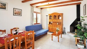 A living room with a blue sofa, wooden dining table, and chairs. There is a cabinet with glass doors and a fireplace. - -Villa with private swimming-pool. HUTG-001429 (l'Escala)