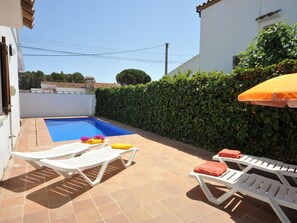 Une piscine avec deux chaises longues blanches et un parasol jaune.