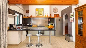 Une cuisine moderne dotée d’un îlot central, d’appareils électroménagers en acier inoxydable et de tabourets de bar.