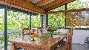 Une table de salle à manger en bois, mise avec des assiettes, des verres et un vase décoratif.