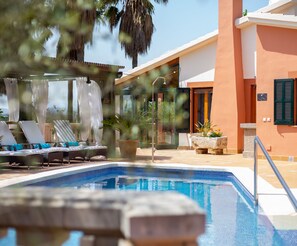 A swimming pool with lounge chairs and a stone planter. - Can Marti - Wonderful villa with pool in a mountain area near Alcúdia (Alcúdia)
