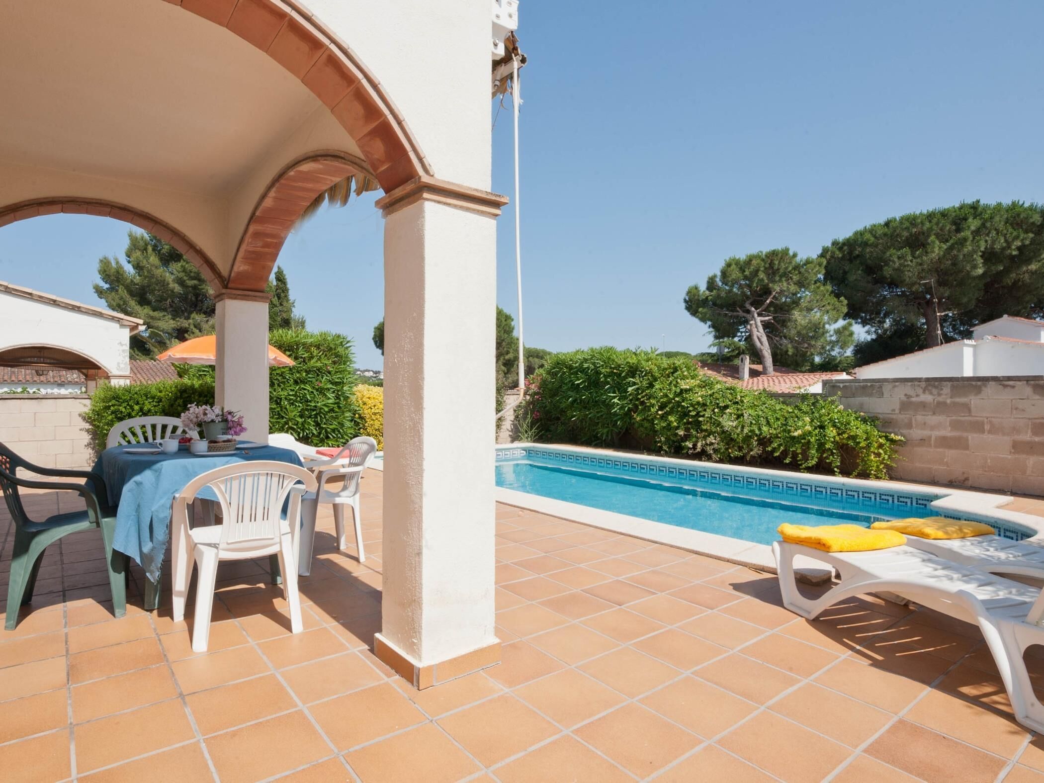 A covered outdoor area with a pool, patio furniture, and a table with chairs.
