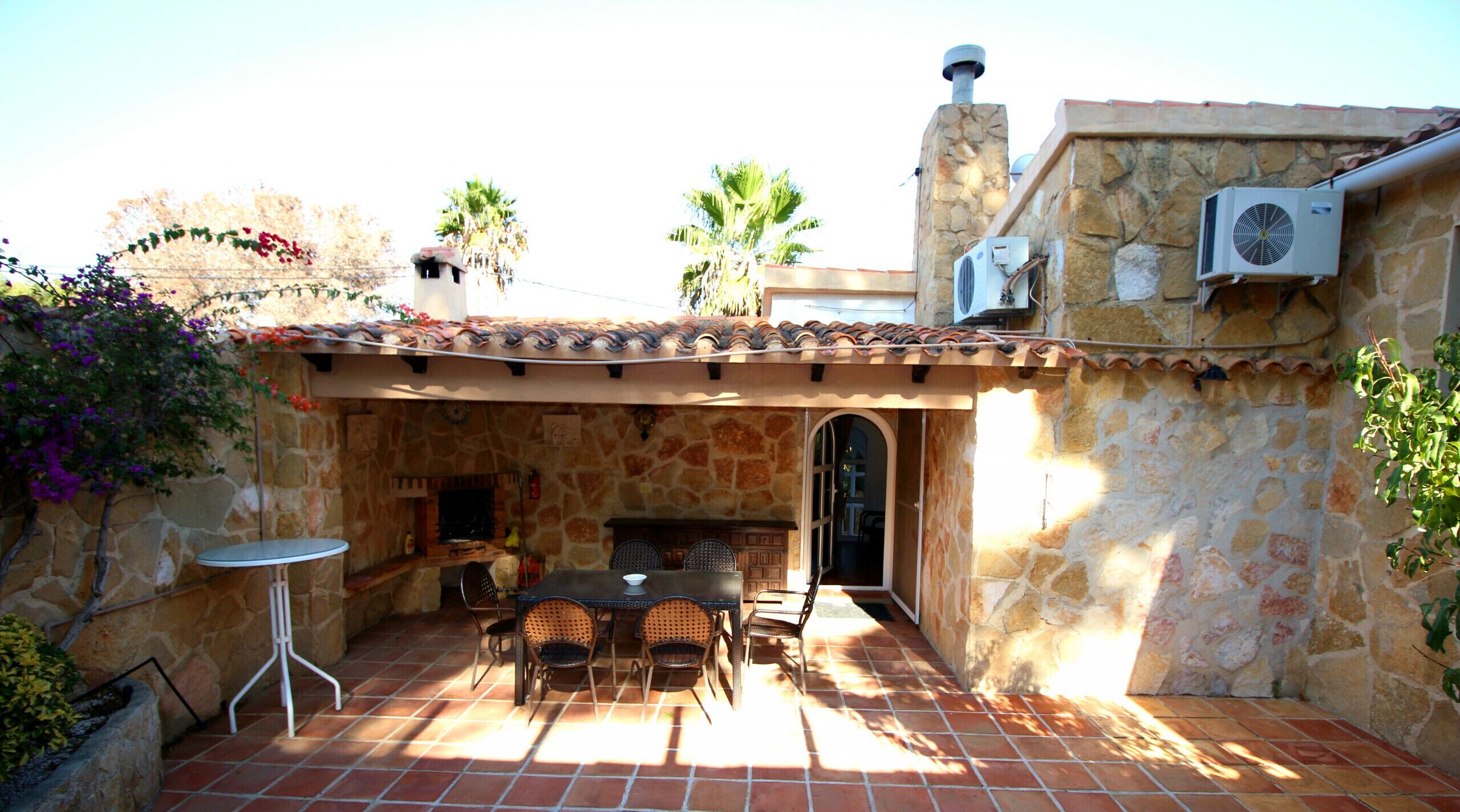 Un patio con muros de piedra, suelo de baldosas y una mesa con sillas.