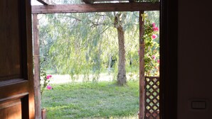 A wooden door leading to a garden with a stone pathway, a tree, and pink flowers. - Villa Collebelvedere - Apartment West - Home Restaurant (Fara Sabina (RI))