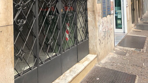 Un edificio con una reja metálica, un escalón pequeño que lleva a la entrada y un letrero que indica que es un establecimiento comercial.